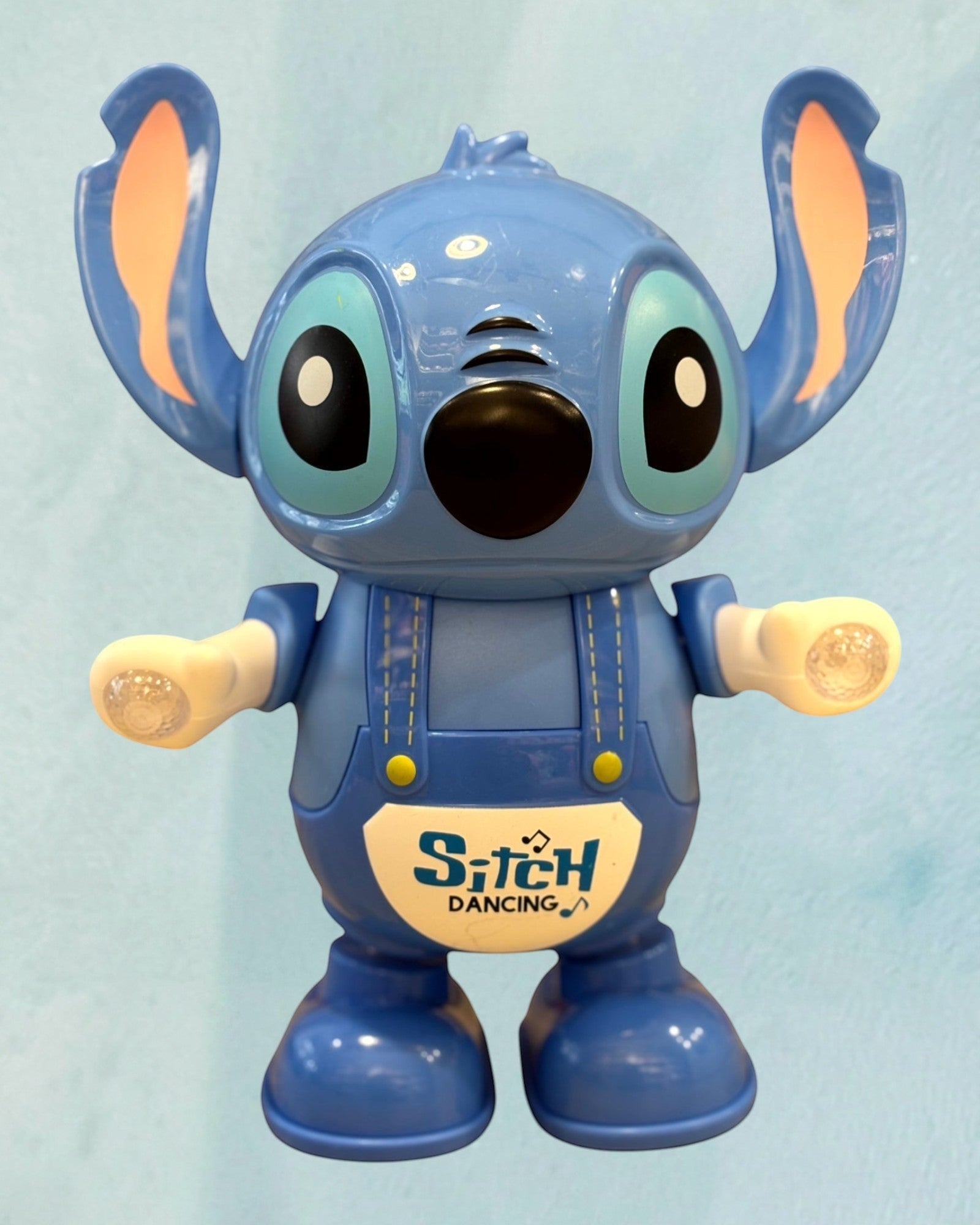 Tagerelsa3ada blue dancing character toy with flashing lights and 'Stitch Dancing' logo on overalls.