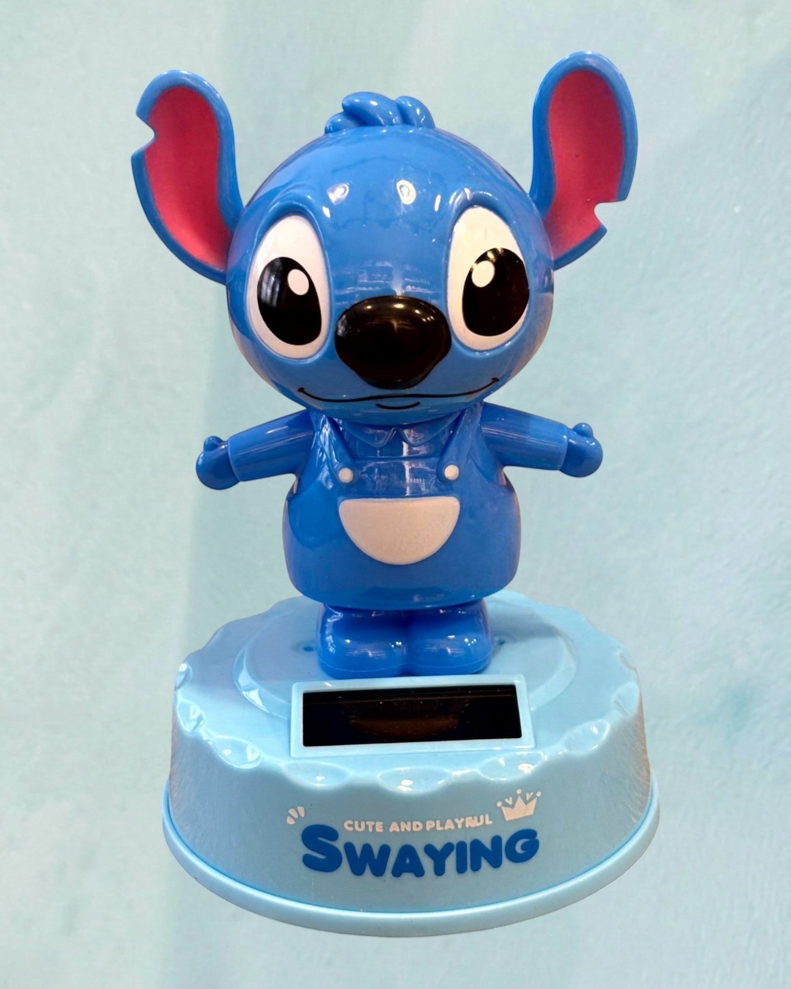 Tagerelsa3ada blue solar-powered dancing Stitch figurine with pink ears and white overalls, swaying on a light blue base.