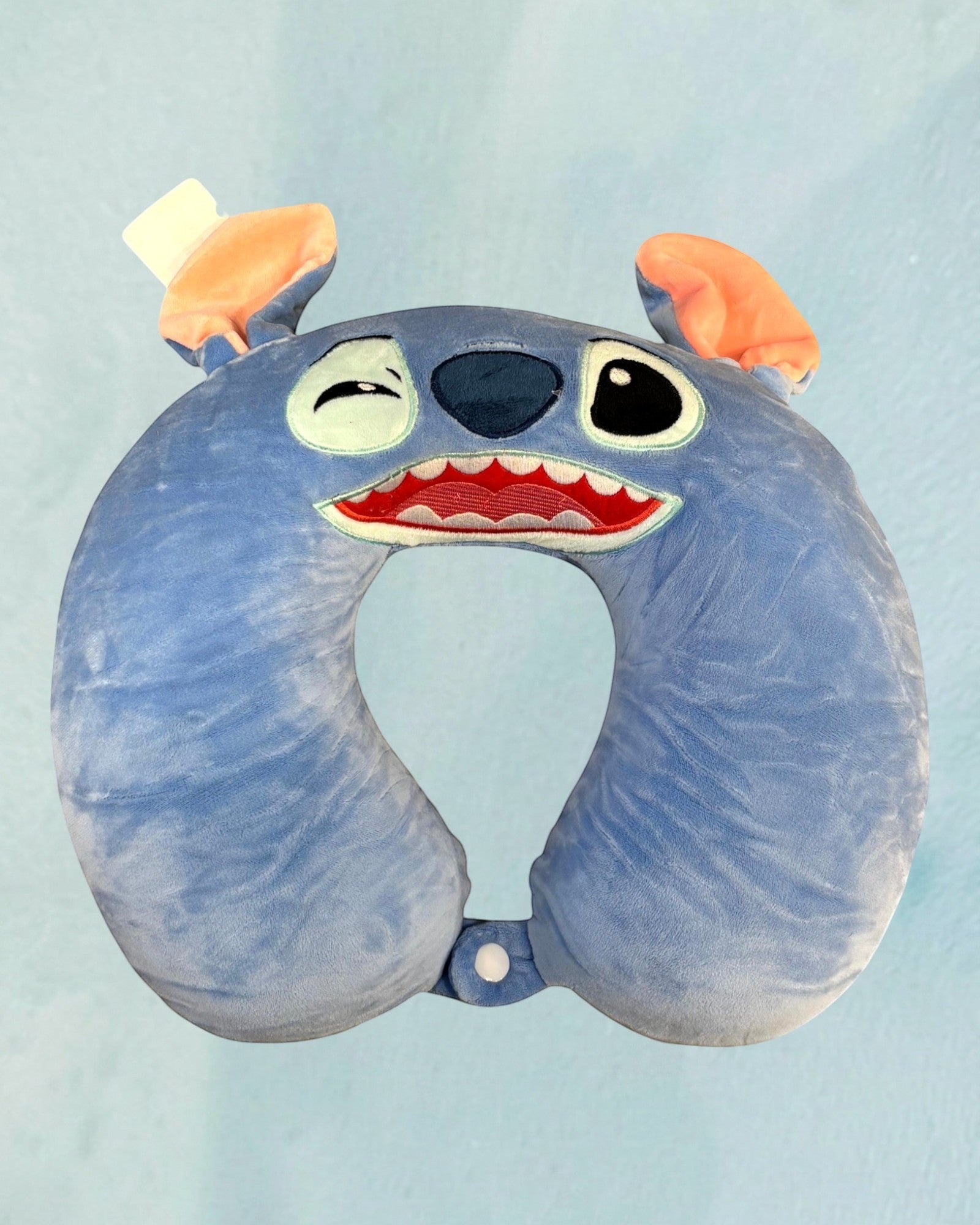 Tagerelsa3ada blue plush character neck pillow with orange ears and a wide, toothy grin, perfect for travel comfort.