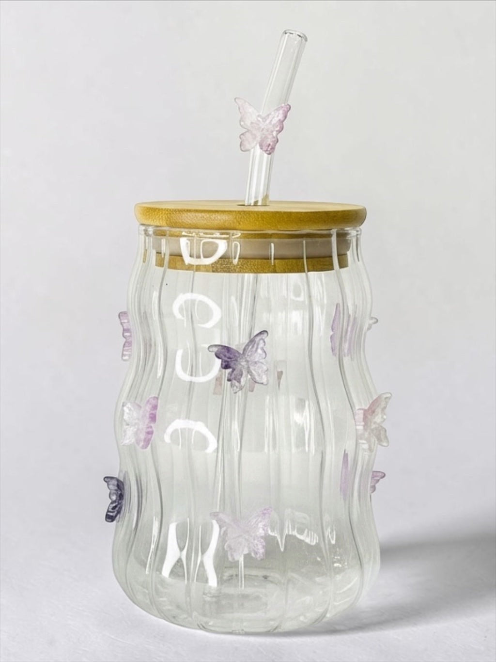 Tagerelsa3ada clear glass tumbler with wavy texture and purple butterfly embellishments, bamboo lid, and glass straw.