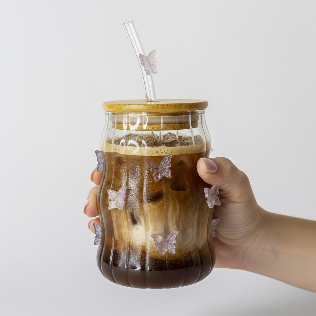 Tagerelsa3ada clear glass tumbler with wavy design, adorned with iridescent purple and pink butterflies. Includes bamboo lid and glass straw with butterfly charm.