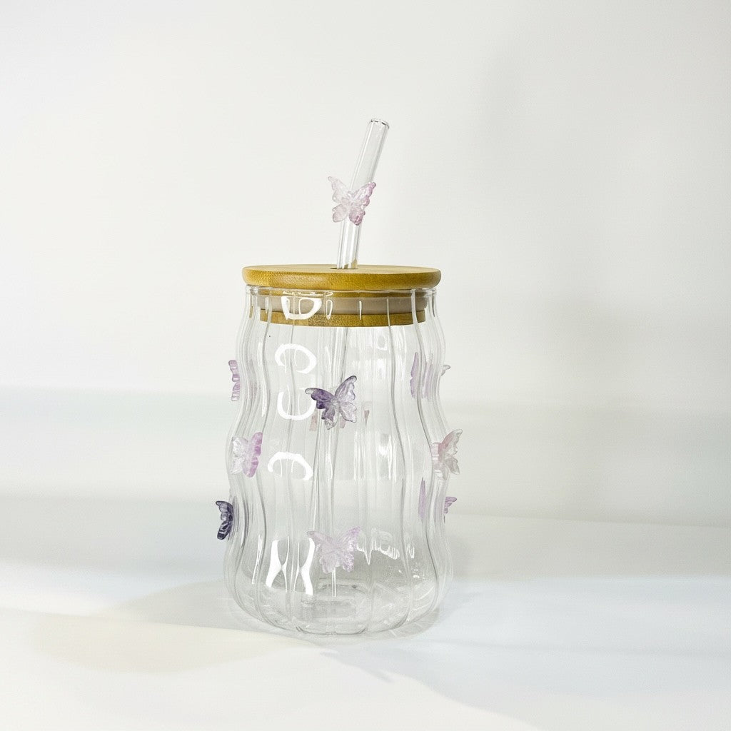 Tagerelsa3ada clear glass tumbler with bamboo lid, featuring purple butterfly embellishments and a glass straw with a butterfly accent.