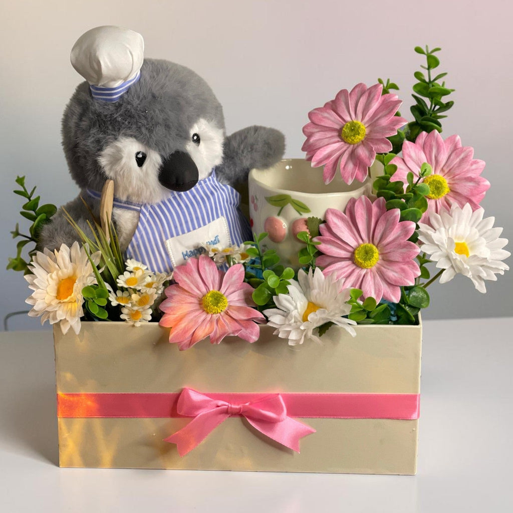 Tagerelsa3ada Chef Penguin Flower Arrangement with pink and white daisies in a cream box with pink ribbon.