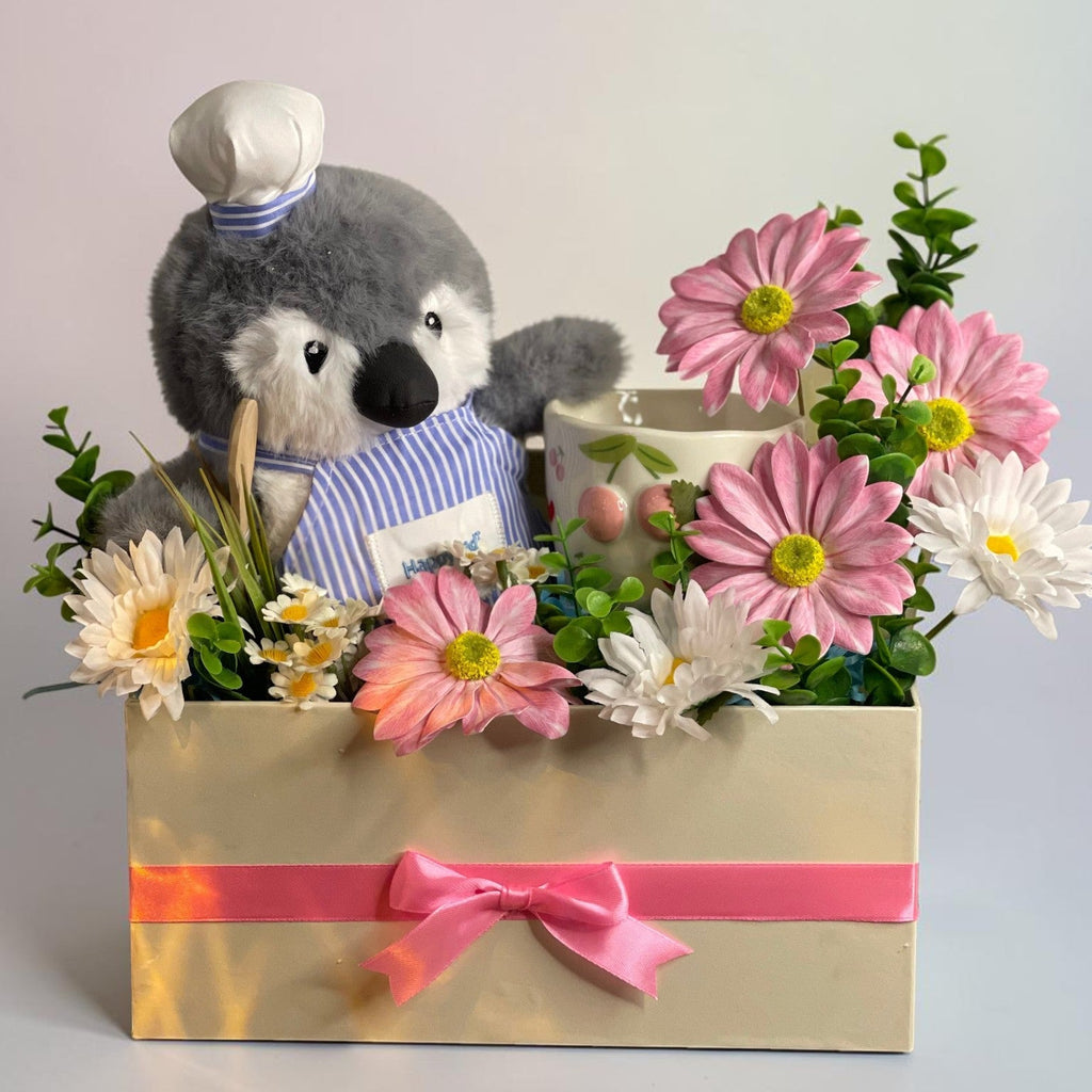 Tagerelsa3ada Chef Penguin Flower Arrangement with pink and white daisies in a cream box with pink ribbon.