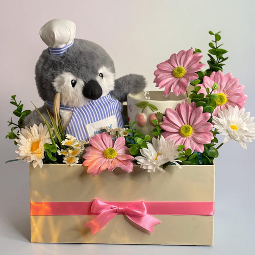Tagerelsa3ada Chef Penguin Flower Arrangement with pink and white daisies in a cream box with pink ribbon.