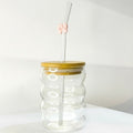 Tagerelsa3ada clear glass tumbler with wavy design, bamboo lid, and glass straw adorned with a pink bow.