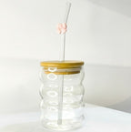Tagerelsa3ada clear glass tumbler with wavy design, bamboo lid, and glass straw adorned with a pink bow.