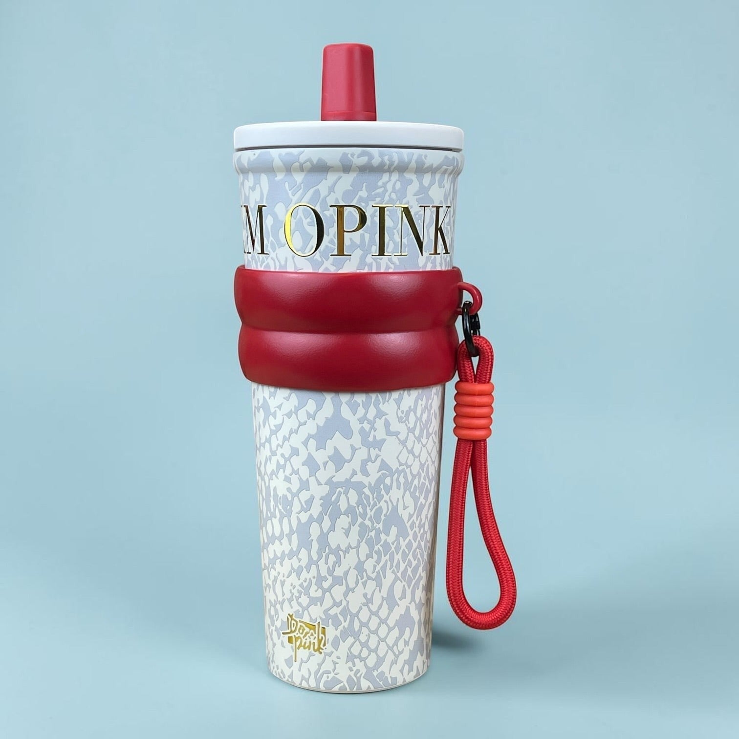 Tagerelsa3ada designer tumbler with strap, featuring a snakeskin pattern in grey and white, gold lettering, and a red strap and lid.