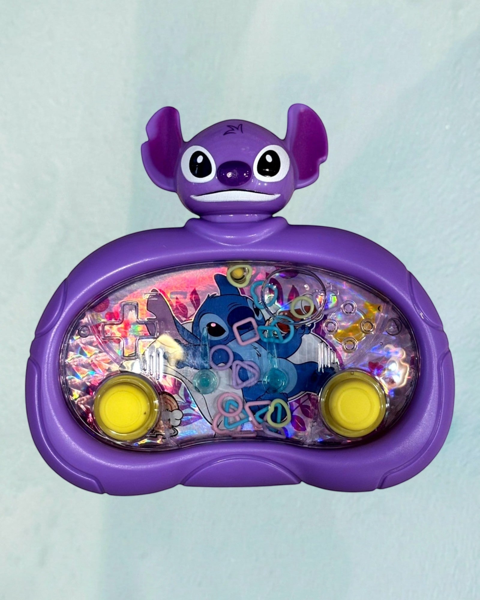 Tagerelsa3ada purple Disney Stitch water game with floating rings and yellow buttons. Features Stitch character on a holographic background.