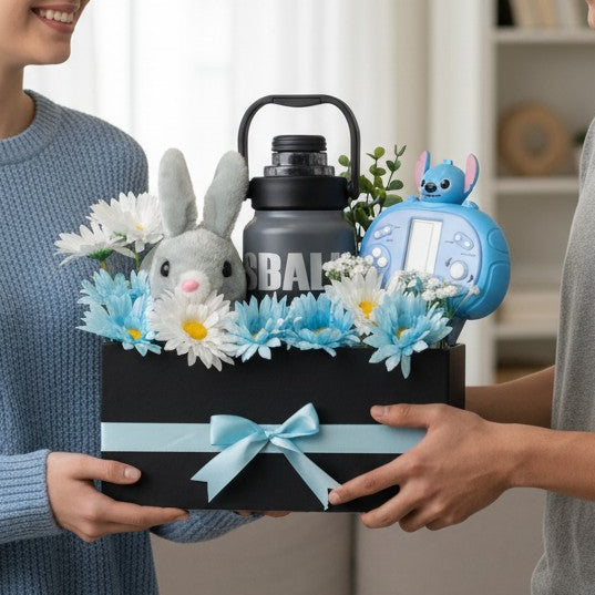 Tagerelsa3ada grey plush bunny, blue and white daisies, grey water bottle, and blue Stitch toy in a black gift box with a light blue ribbon.