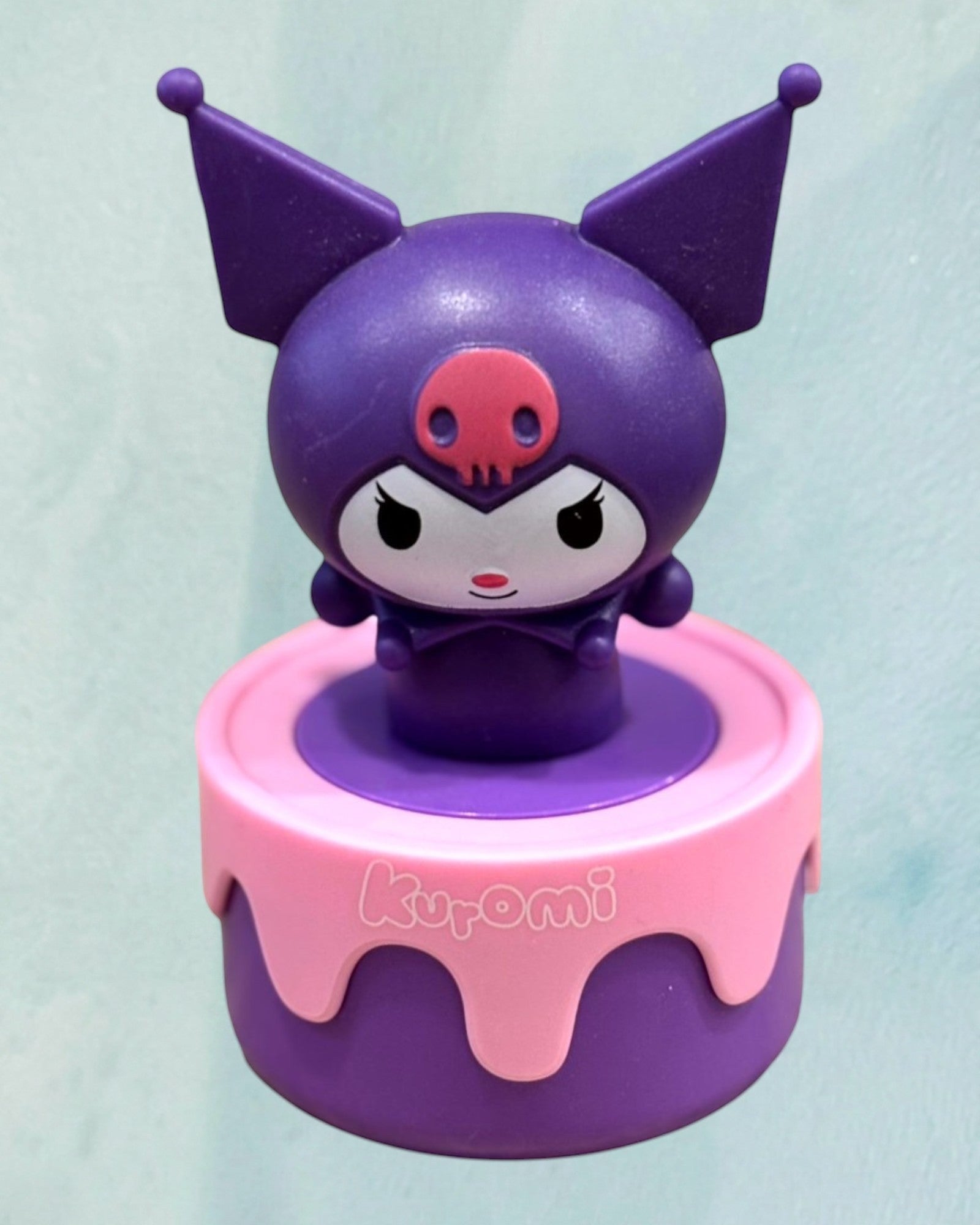 Tagerelsa3ada purple Kuromi figurine on a pink and purple cake-shaped base.