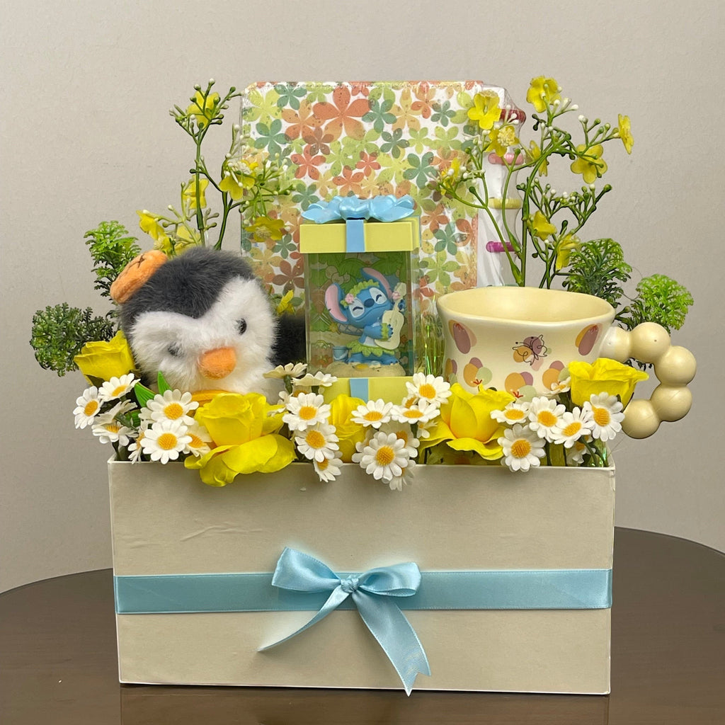 Tagerelsa3ada cream gift box with penguin plush, Stitch figurine, yellow roses, daisies, and a decorative mug.