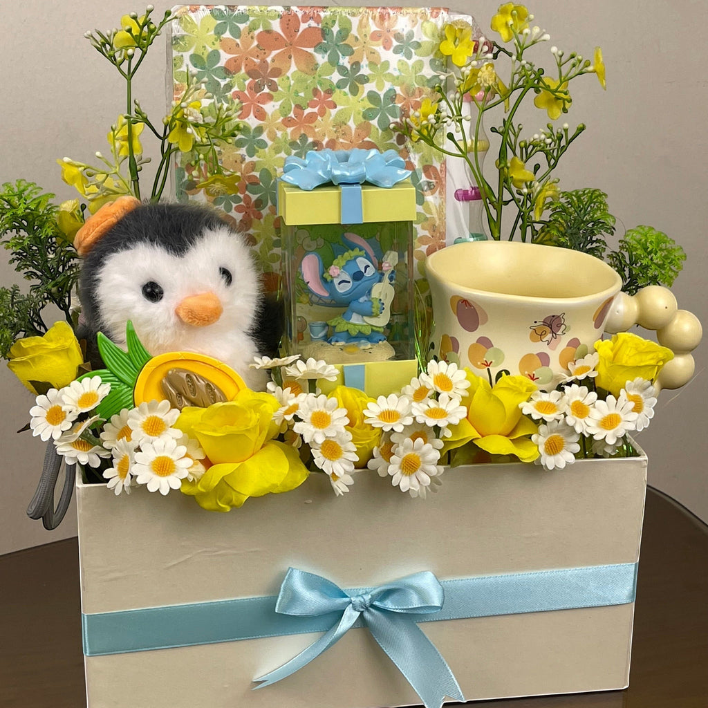 Tagerelsa3ada Penguin and Stitch gift box with yellow roses, daisies, plush penguin, Stitch figurine, and mug.