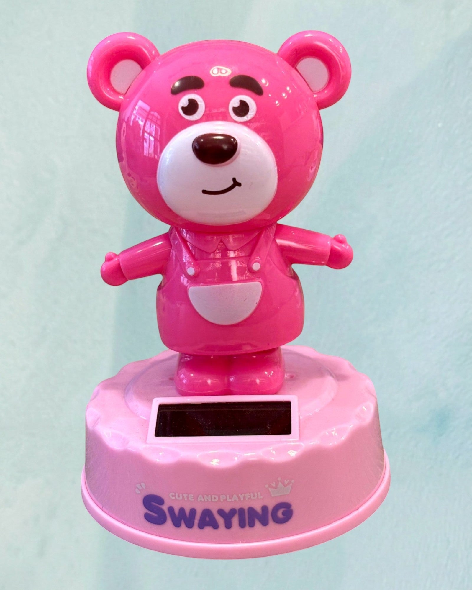 Tagerelsa3ada pink solar-powered dancing bear figurine wearing overalls, with a solar panel on its base.