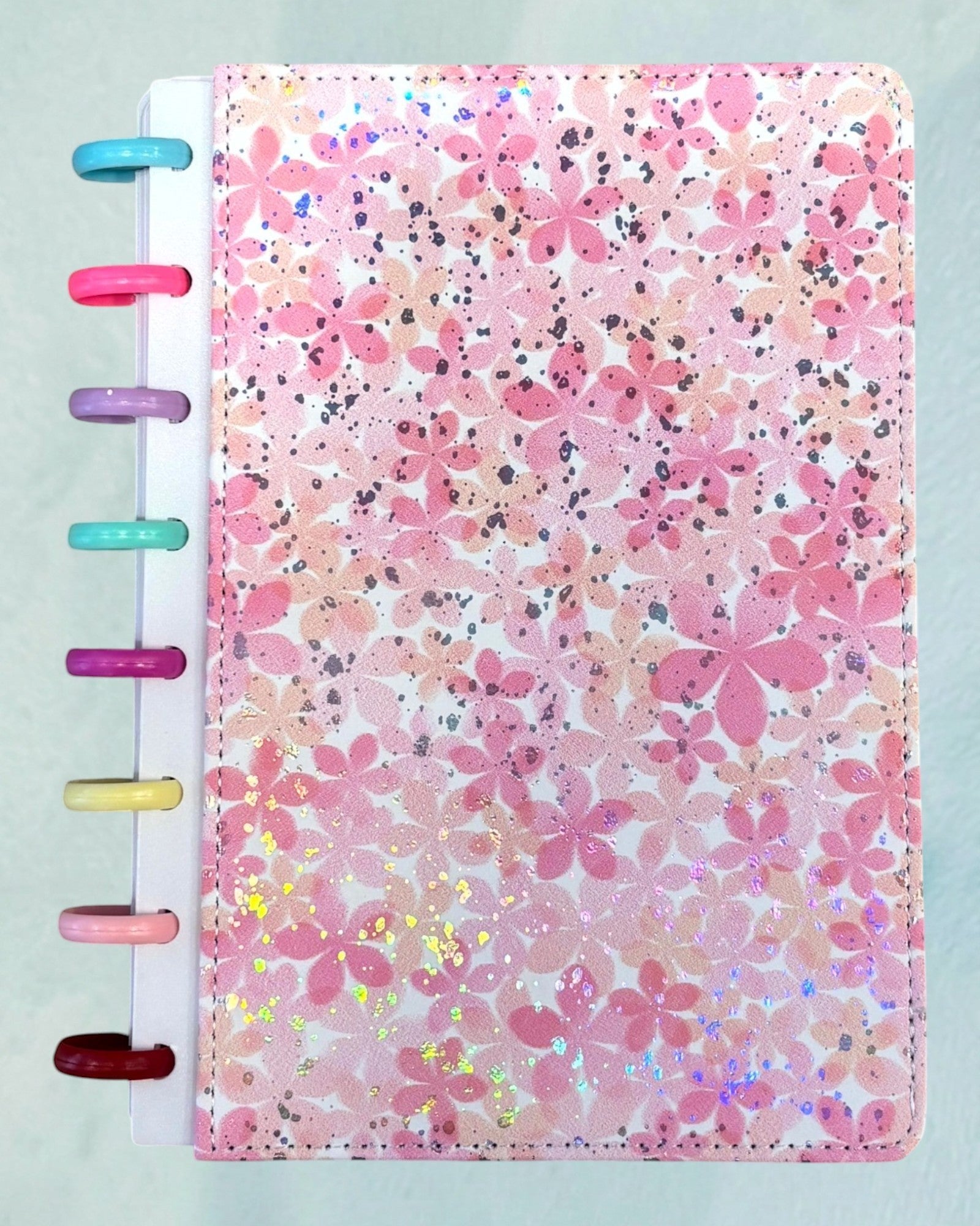 Tagerelsa3ada pink floral discbound planner with holographic glitter accents and colorful plastic discs.