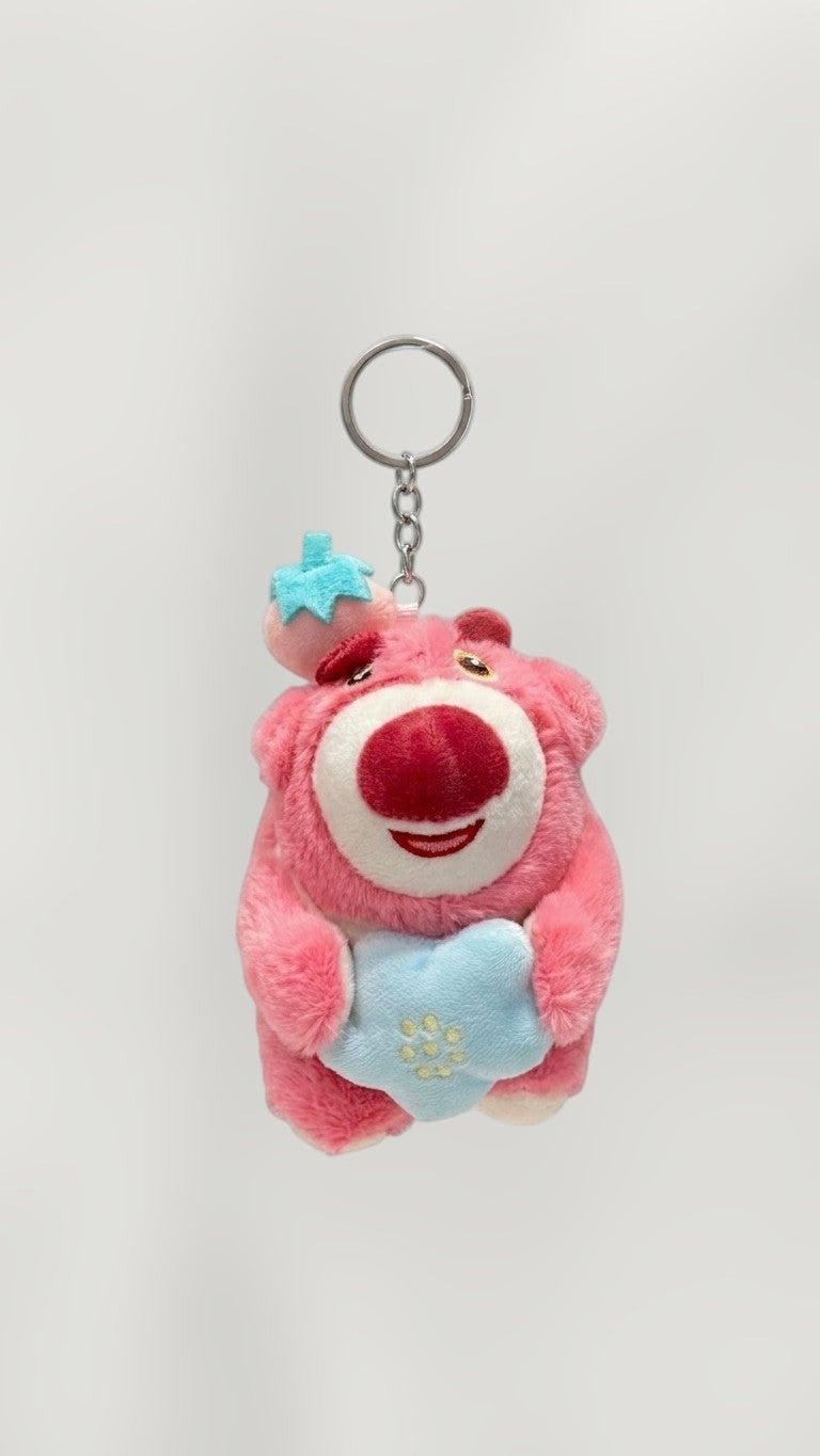 Tagerelsa3ada pink plush bear keychain holding a blue star with embroidered flowers, wearing a strawberry hat.