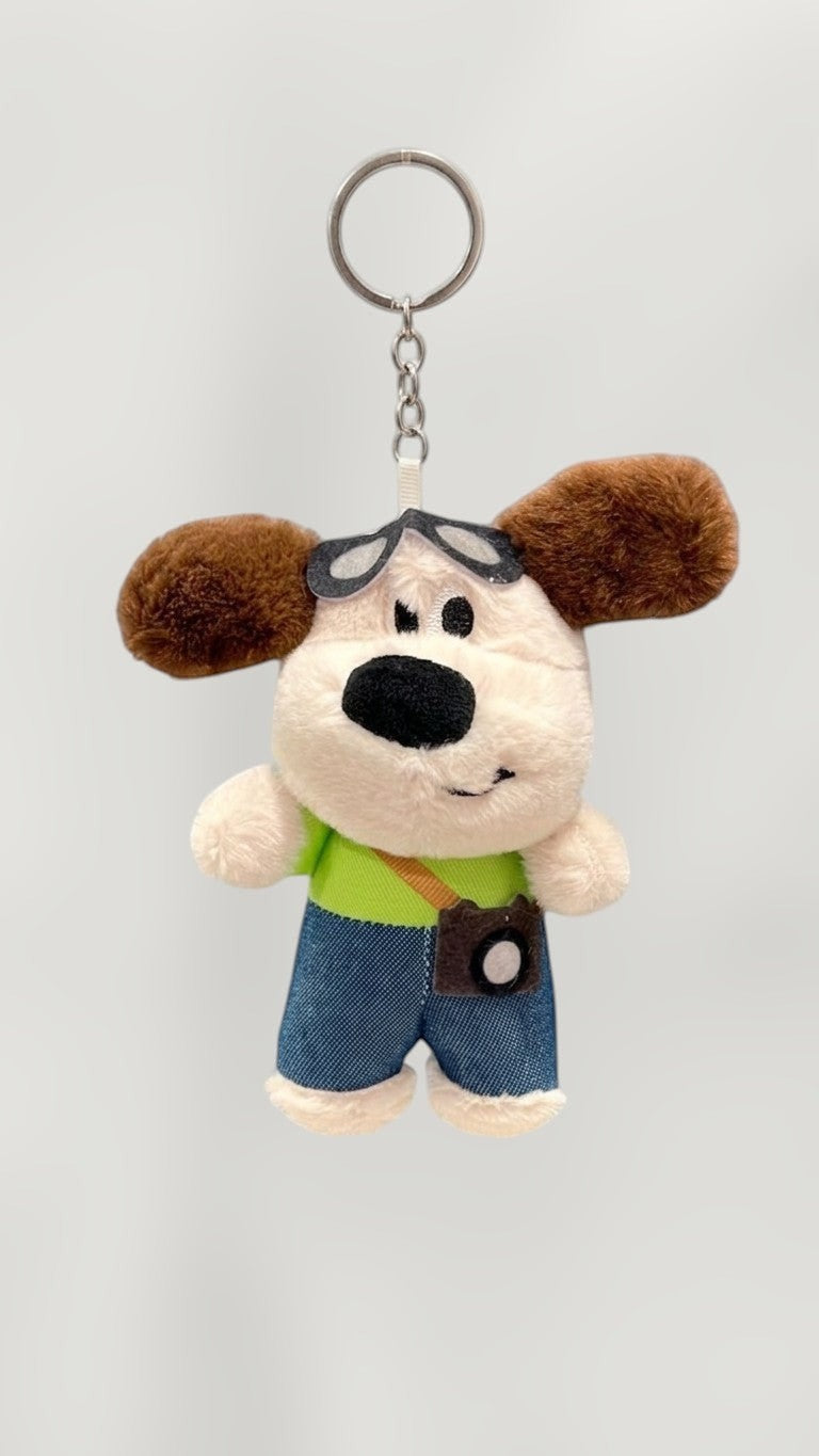 Tagerelsa3ada plush dog keychain with camera accessory, aviator goggles, and denim shorts.