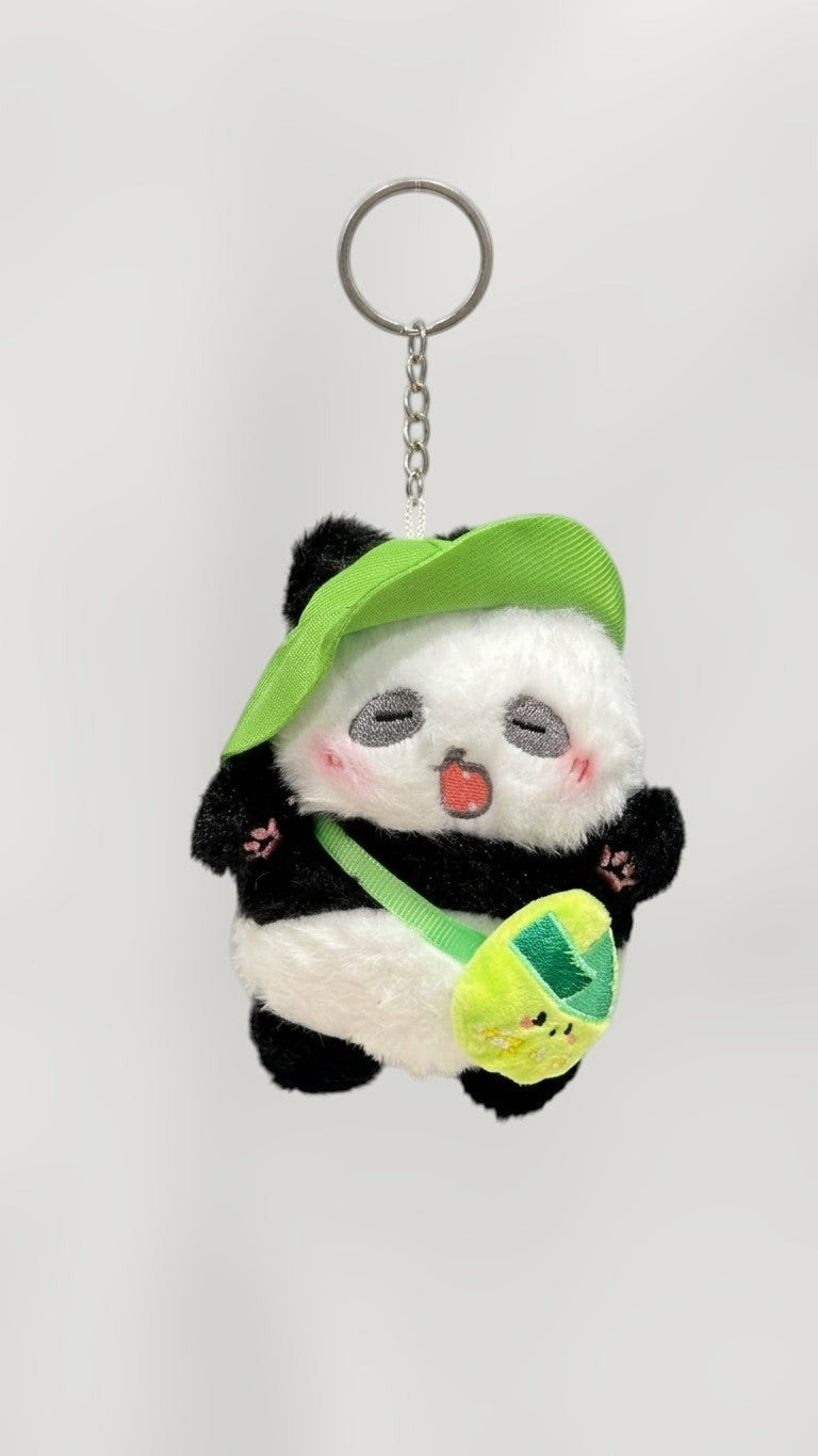 Tagerelsa3ada plush panda keychain with green hat and bag, black and white fur, cute sleepy expression.