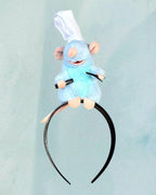 Tagerelsa3ada blue plush rat character headband with chef hat and embroidered details, holding black utensils.