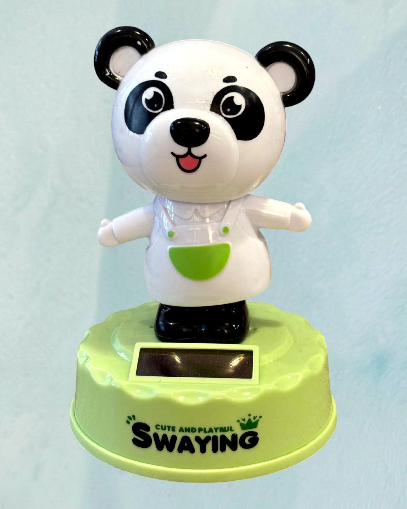 Tagerelsa3ada solar powered dancing panda figurine wearing a white shirt and green apron, swaying on a lime green base.