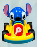 Tagerelsa3ada blue Stitch character in a yellow plastic racing car toy with black wheels and red accents.